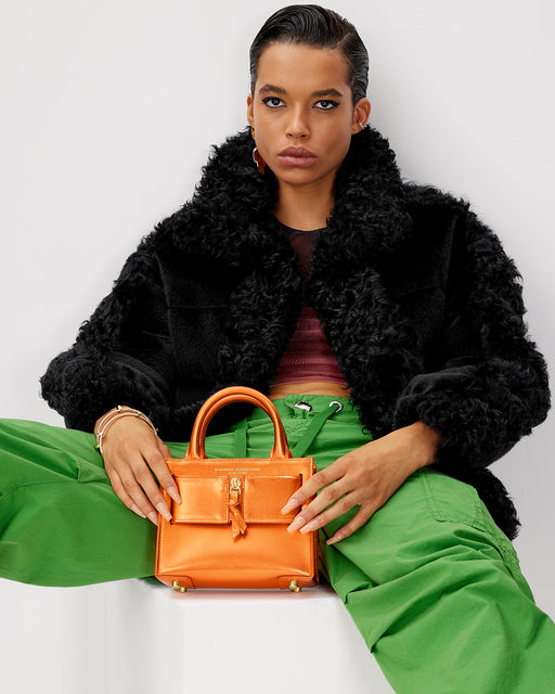 Model posing with Kuei Bag in metallic orange with leather silver zipper 