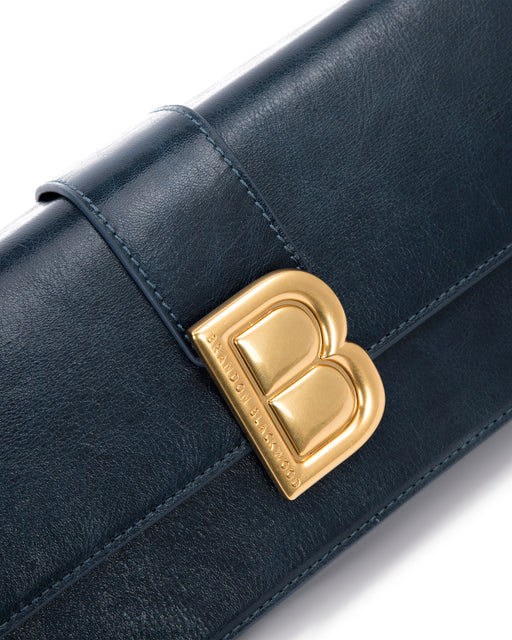Angled close up of Nia Bag with navy cracked leather with brass logo magnetic closure