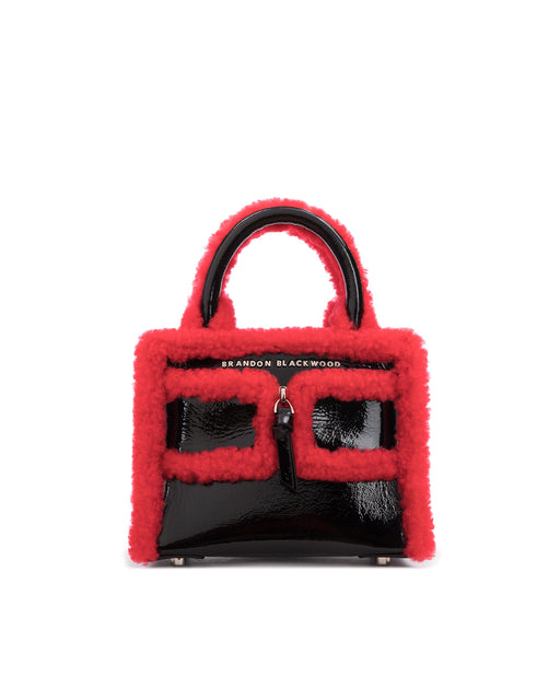 Front of Kuei Bag in black patent leather with bright red shearling trim and black patent leather with bright red shearling trim with leather and silver zipper 
