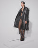 Side view of Model wearing the Sena trench walking on treadmill with ostrich feathers blowing in wind