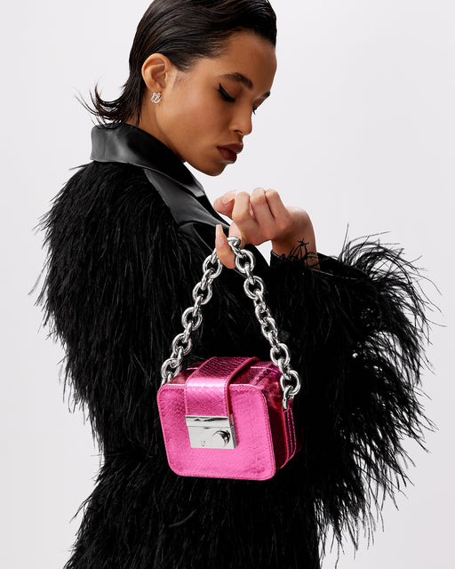 Model posing with Caro Buckle Bag in hot pink python with silver chunky chain handle and silver clasp buckle 