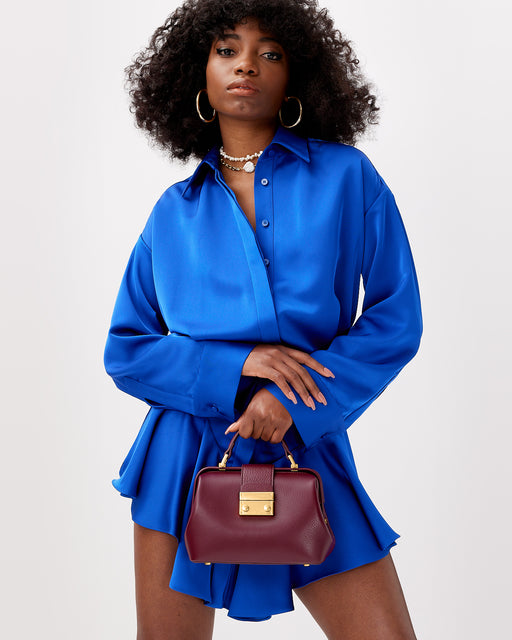 Model posed with Elizabeth Doctor Bag in burgundy leather with leather handle brass clasp buckle