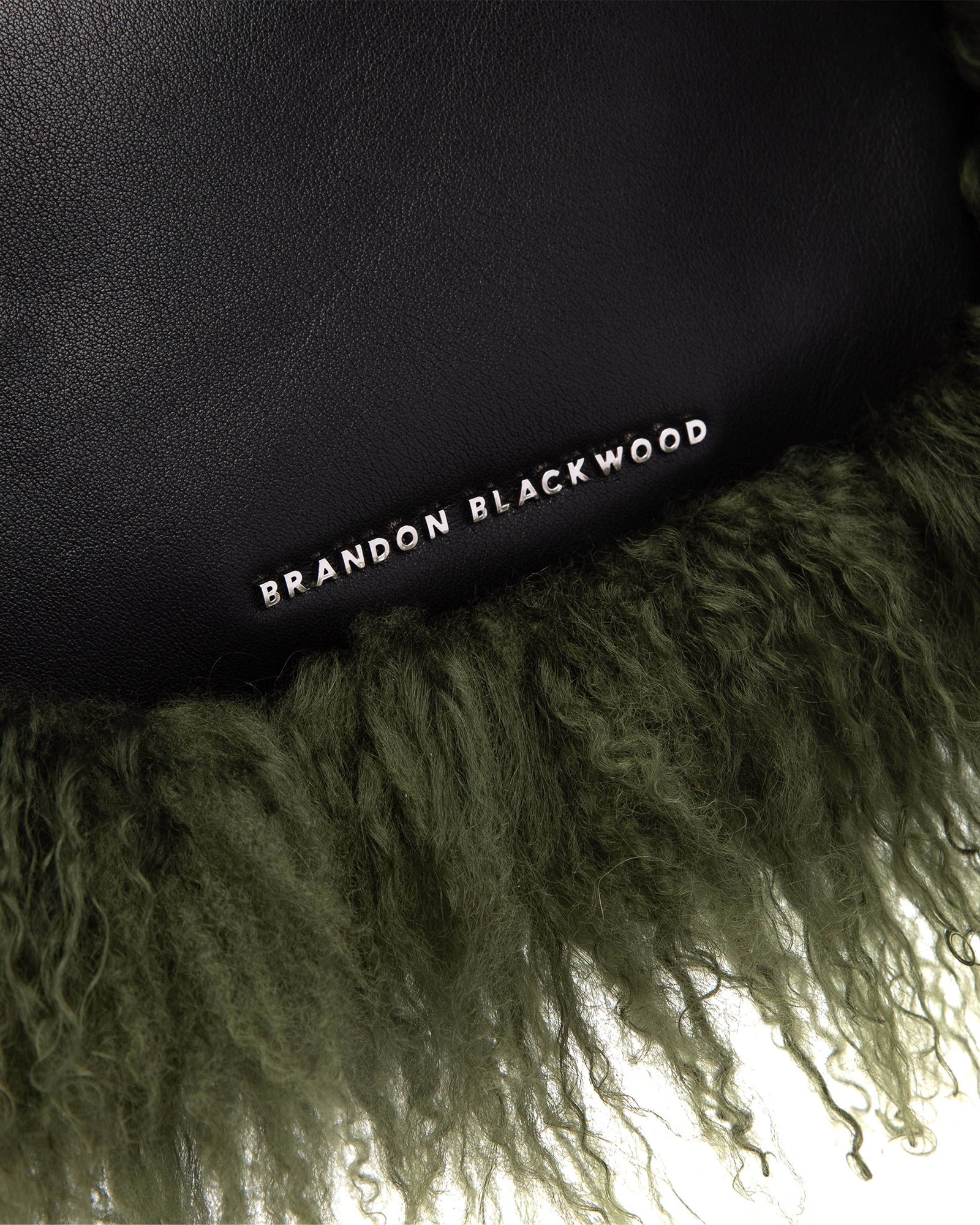 Angled close up of Cortni Bag in black leather with green wool brandon blackwood logo hardware