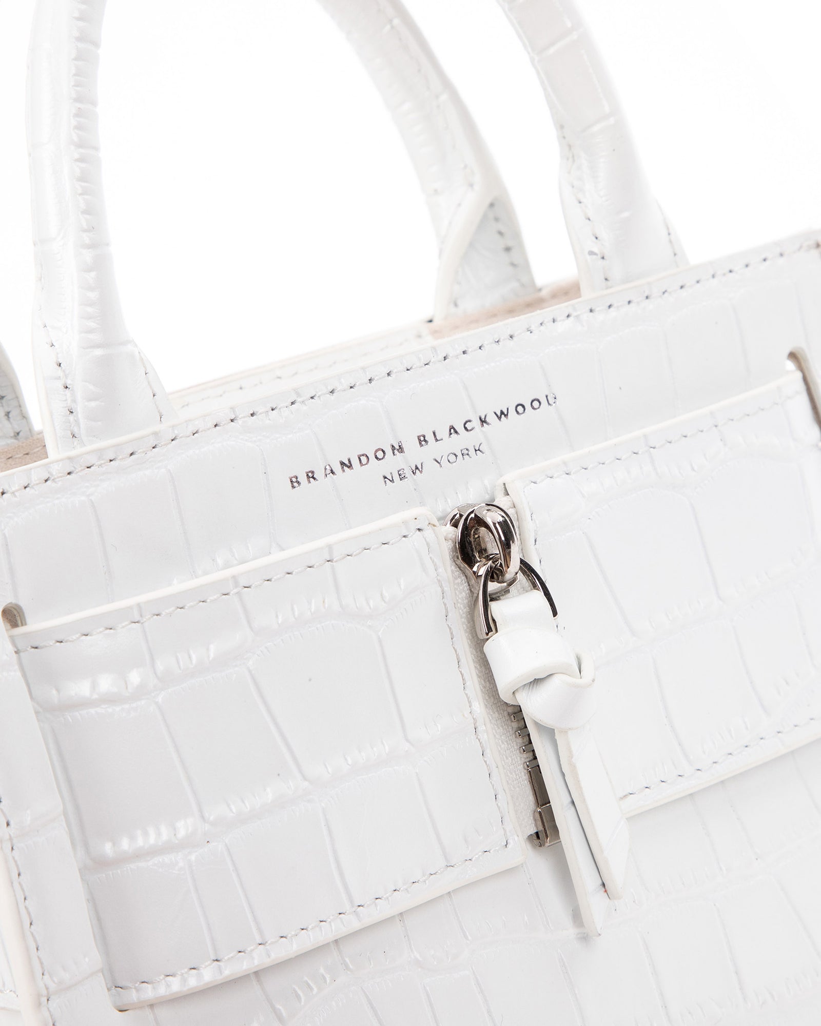 Angled close up of Kuei Bag in white croc embossed leather