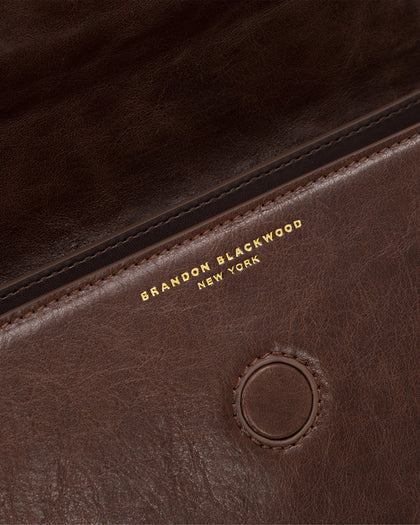 Angled close up of Nia Bag with brown cracked leather with brass logo magnetic closure  thumbnail 4