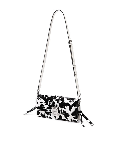 Nia Bag with black and white cow print with cow print strap with silver logo magnetic closure hanging with strap thumbnail 2