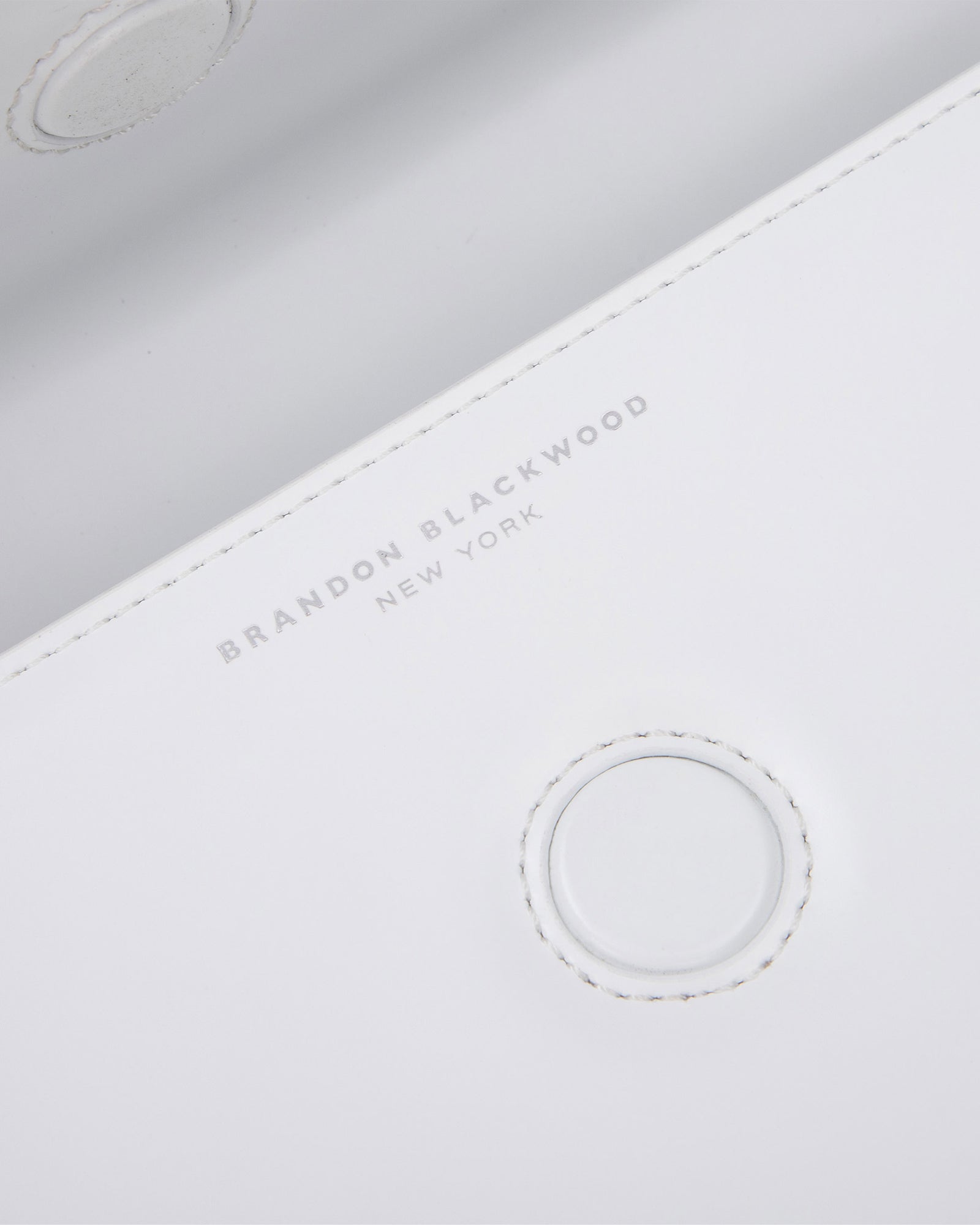 Angled close up of Nia Bag with white hard leather with silver logo magnetic closure 