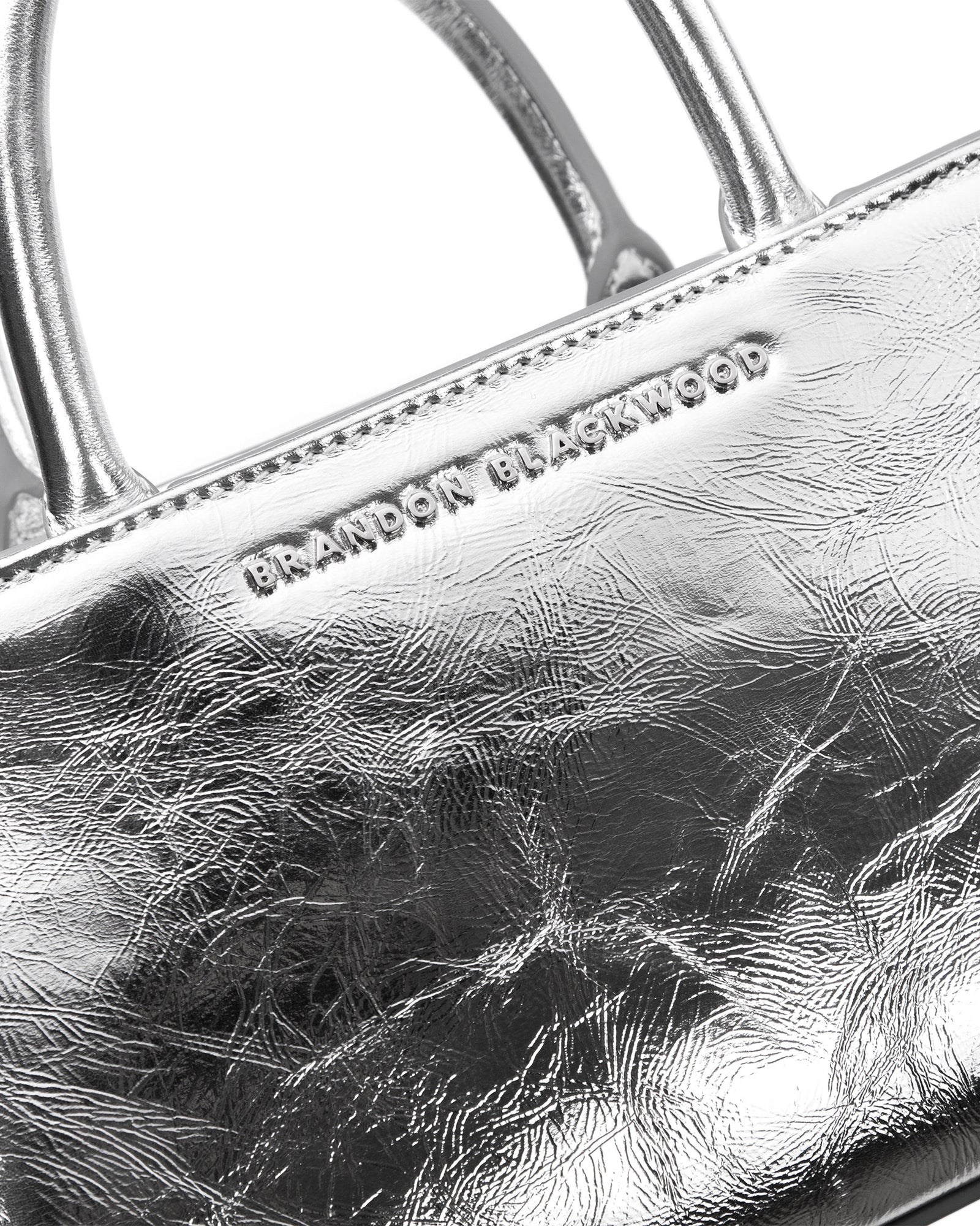 Angled close up of Arlen Bag, metallic silver leather body with leather handle, Brandon Blackwood hardware logo