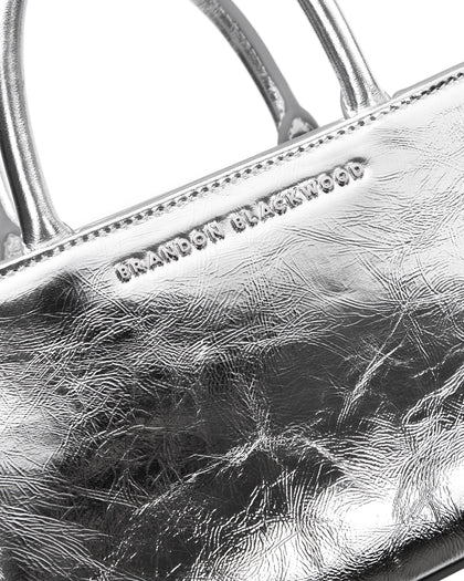 Angled close up of Arlen Bag, metallic silver leather body with leather handle, Brandon Blackwood hardware logo thumbnail 4