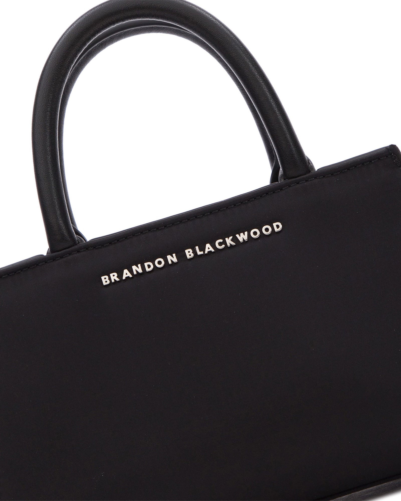Angled close up of Arlen Bag, black nylon body with leather handle, Brandon Blackwood hardware logo
