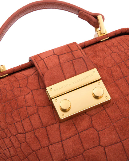 Angled close up of Elizabeth Doctor Bag in rust croc suede with brass clasp buckle with embossed logo thumbnail 3