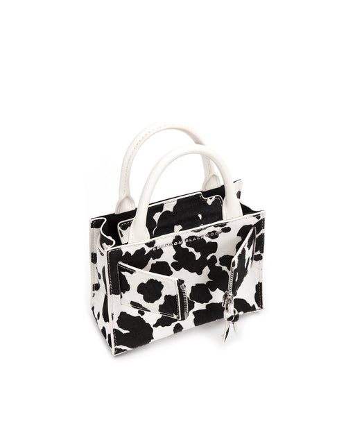 Angled over head view of wide open Kuei Bag in black and white cow print ponyhair with ponyhair handle ponyhair silver zipper 