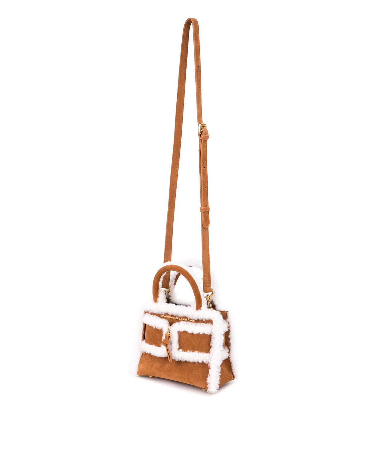 Angled over head view of wide open Kuei Bag intan suede with shearling edges with tan suede and shearling edges handle zipper hanging from strap