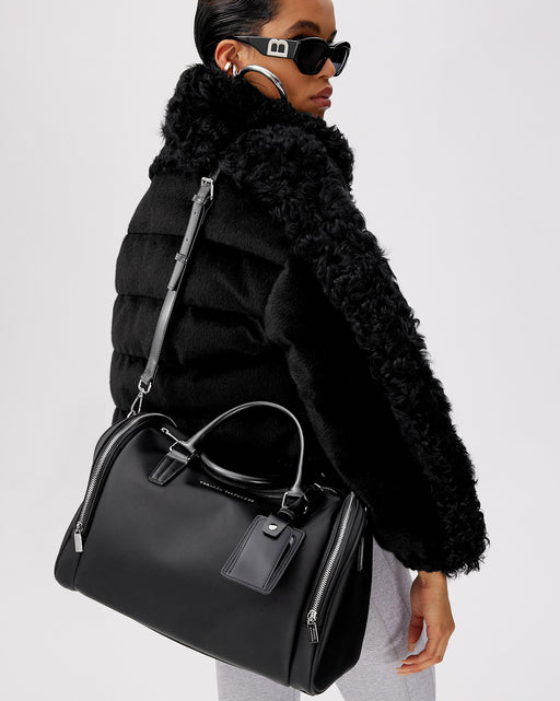 Model posed with Medium Duffle in black nylon with silver Brandon Blackwood Logo black leather handle and double sided silver zipper closure 
